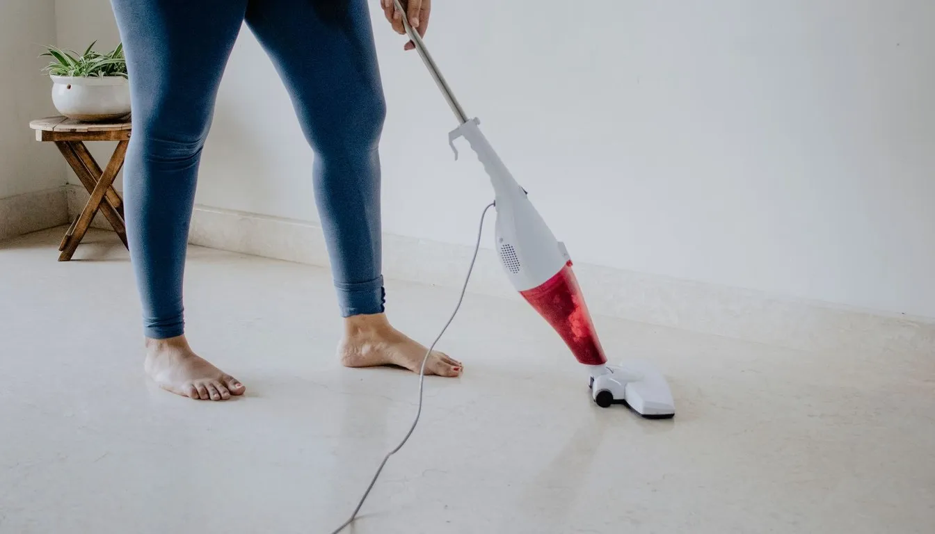 Person vacuuming a floor with a stick vacuum