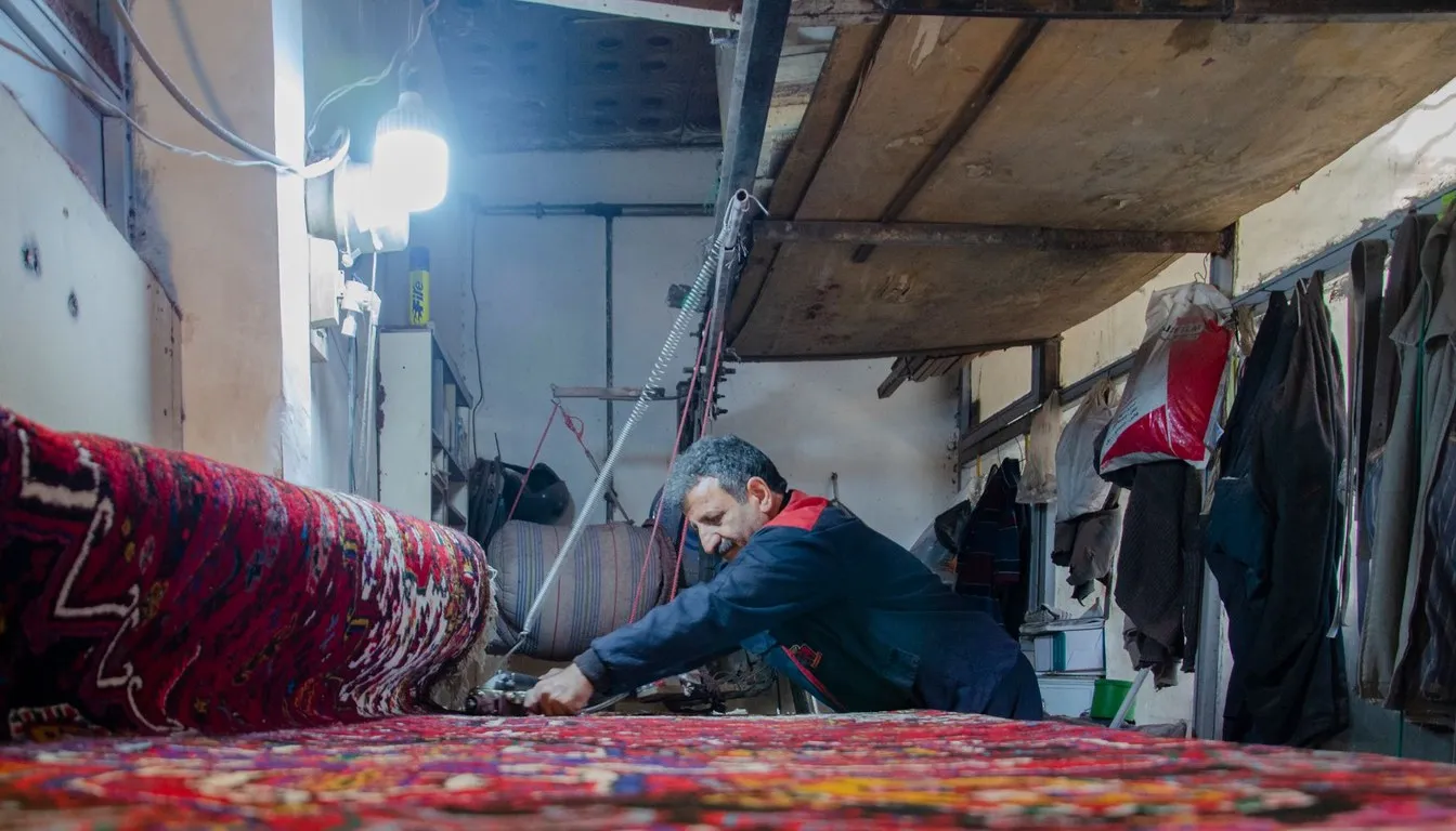 Worker washing a large patterned rug in a cleaning workshop