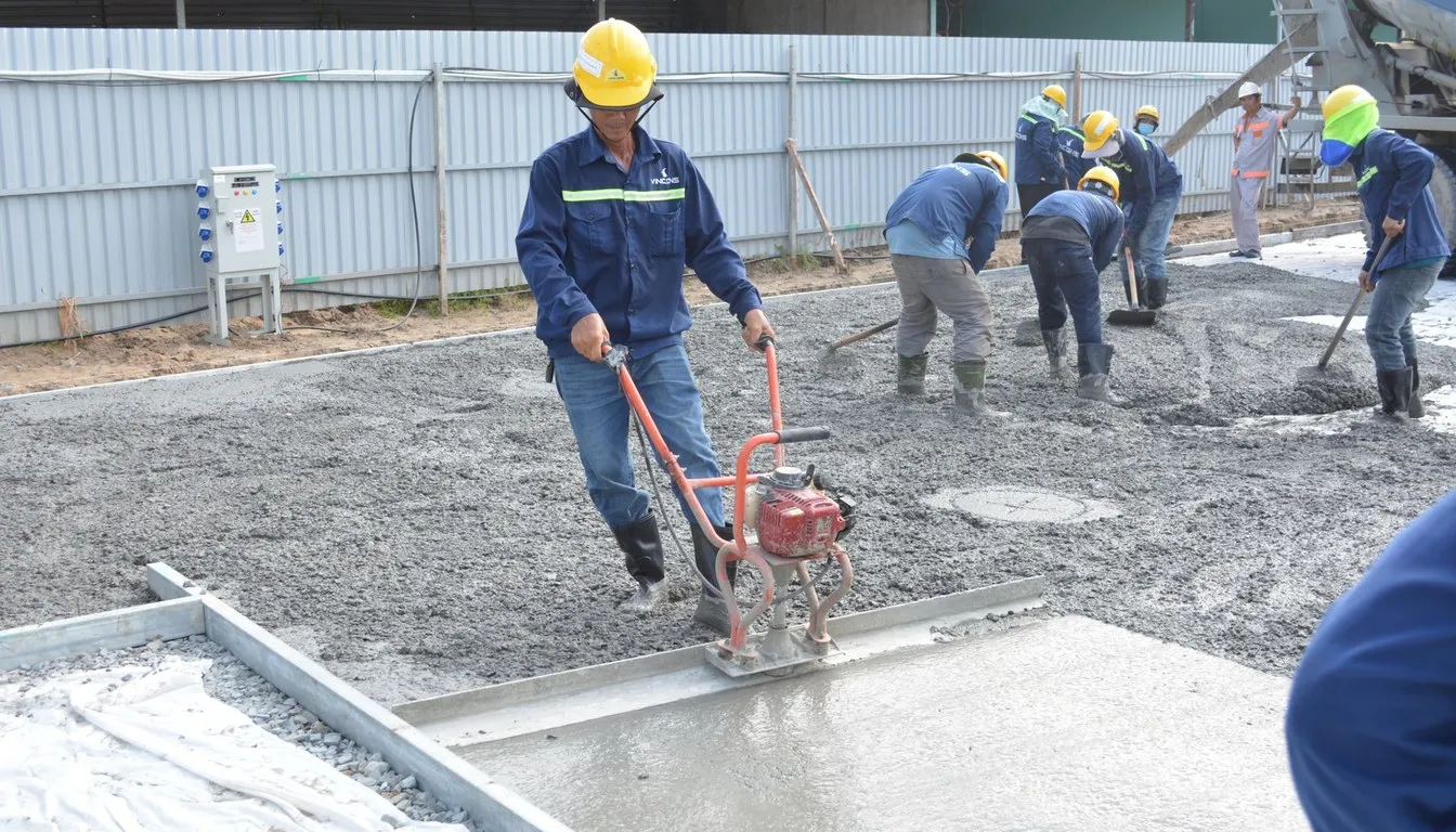 Workers pouring and leveling a concrete slab