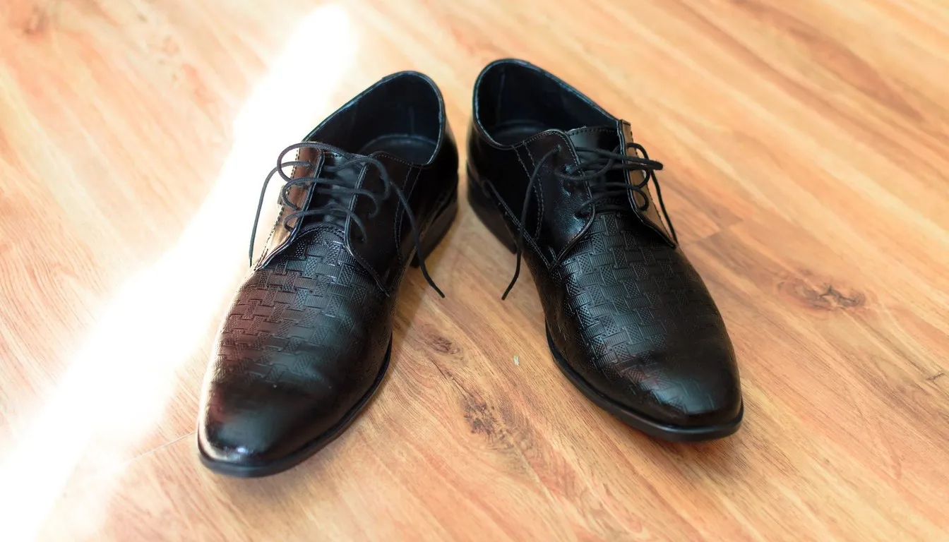 Pair of polished black leather dress shoes on a wooden floor