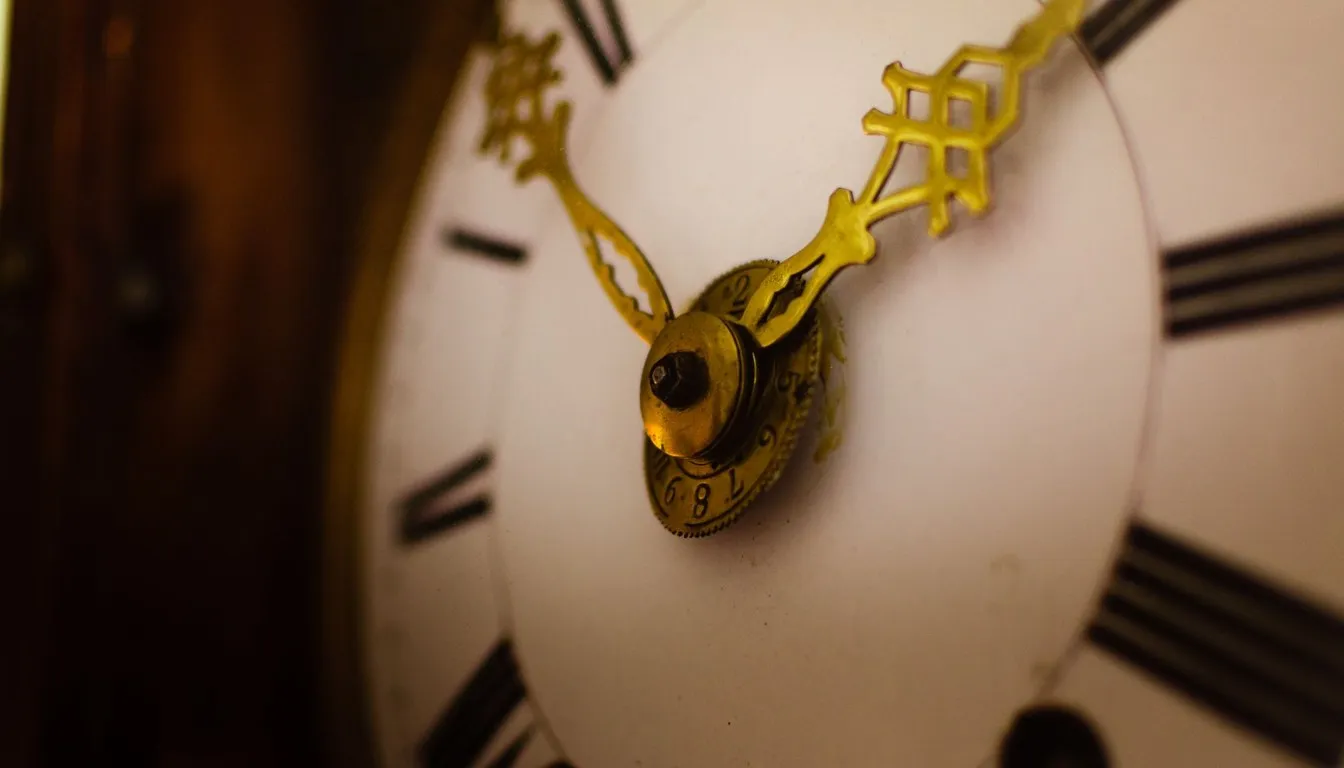 Close-up of ornate gold hands on a grandfather clock face