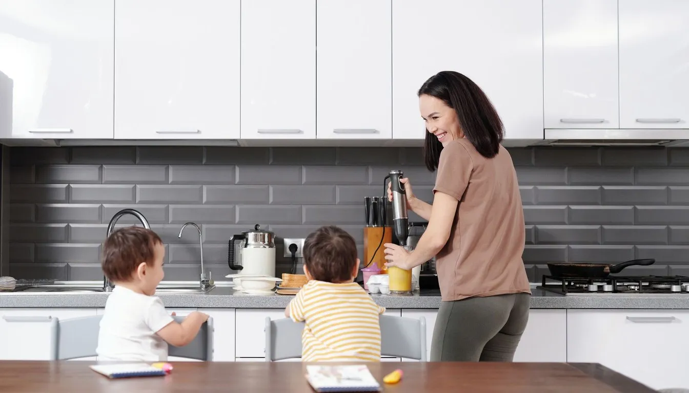Mother using an immersion blender with children watching