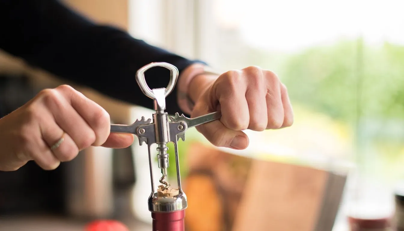 Hands drawing a cork with a corkscrew