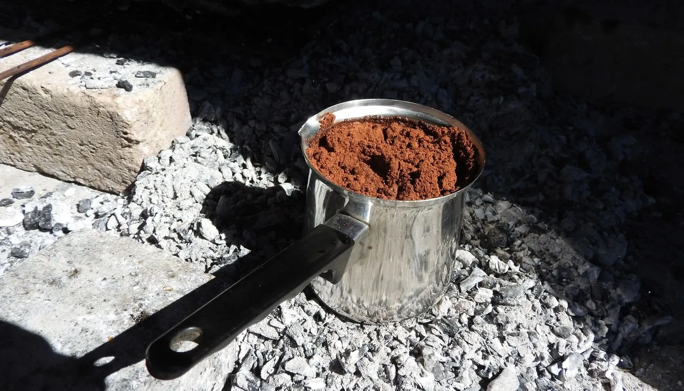 Scorched saucepan resting on charcoal and ash