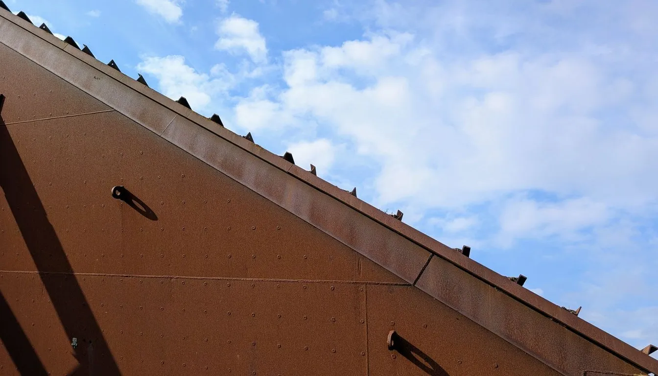 Rusted metal roof edge against a cloudy sky