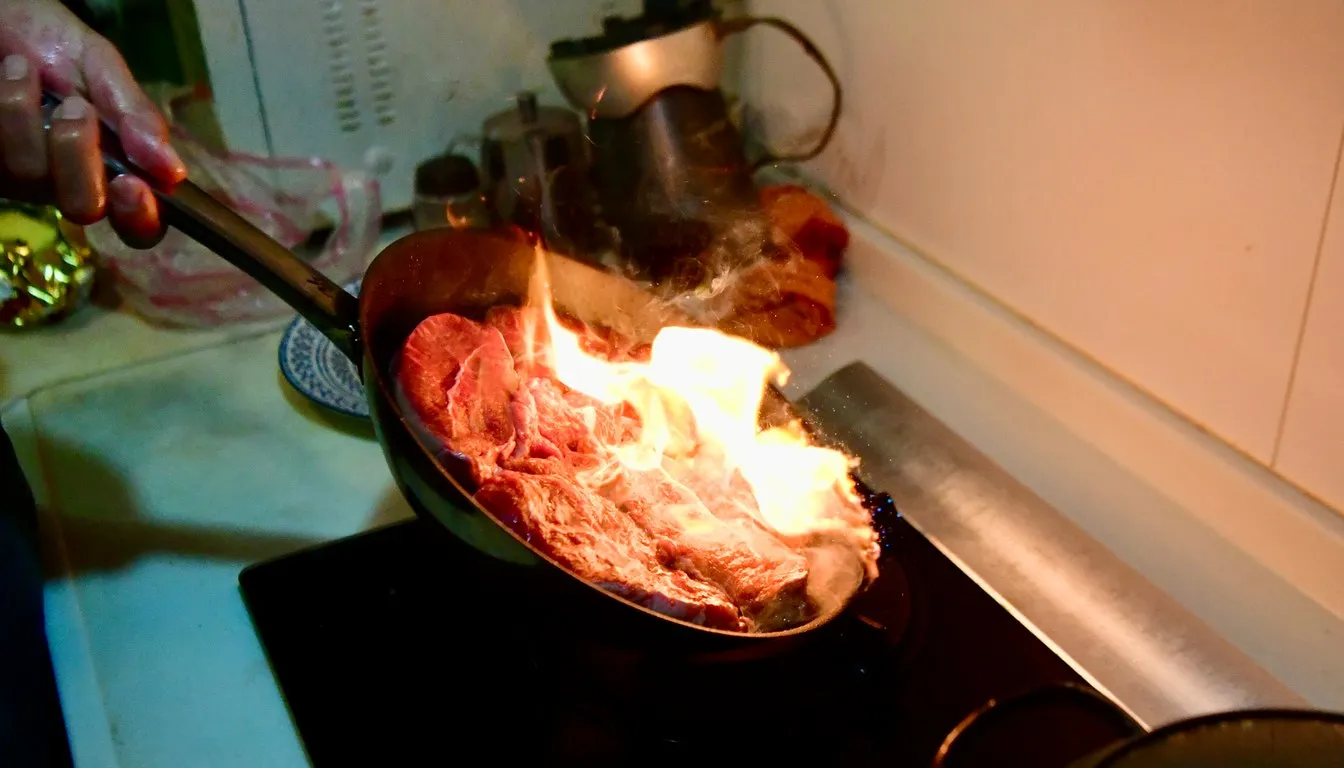 Meat searing over open flame in a grill pan