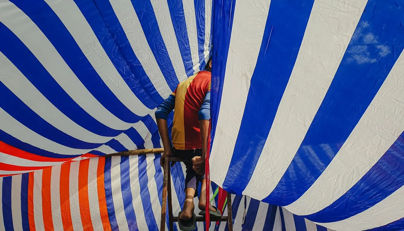 Worker beside a striped fumigation tent covering a house