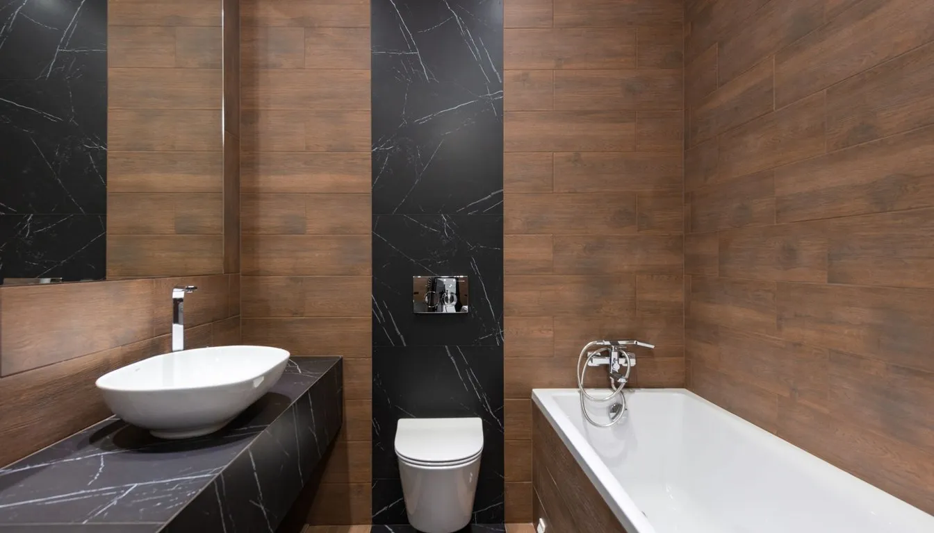 Dark-tiled bathroom with a wall-hung toilet, basin, and bath
