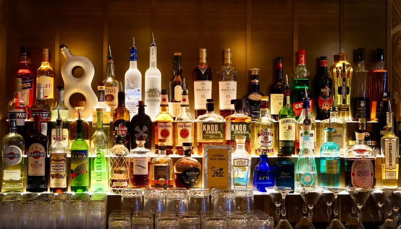 Backlit bar shelf of whiskey bottles and glasses